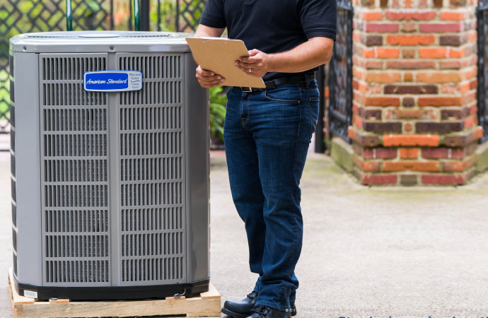A man standing behind a HVAC unit.