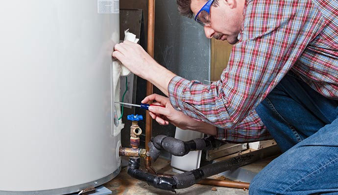 Technician using a screwdriver to inspect components on aging heating equipment