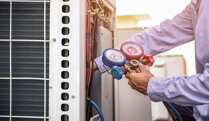 A person is checking AC refrigerant using analog gauge set