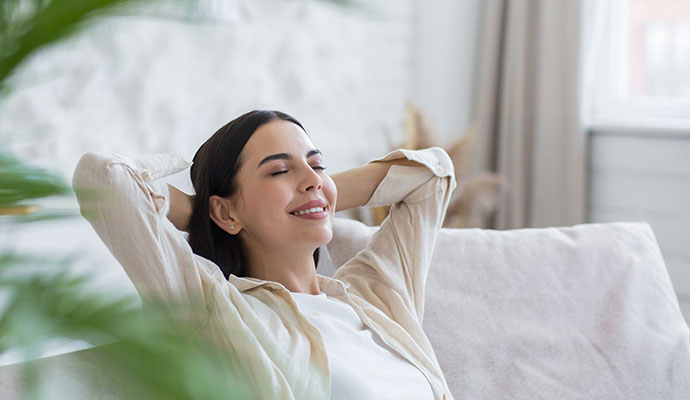 Woman relaxing comfortably at home breathing clean purified indoor air