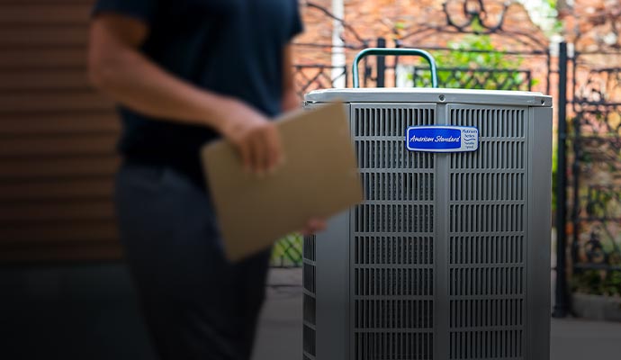 Expert technician in front of American Standard AC unit