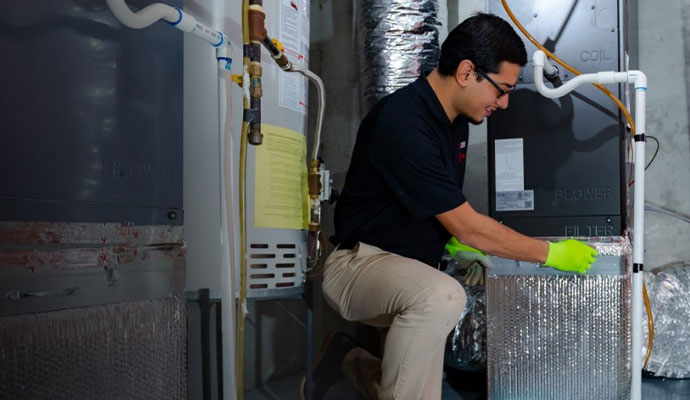 A technician working on a residential furnace system in a basement