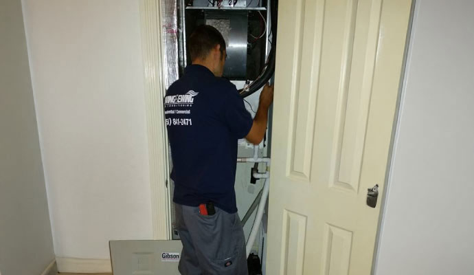 HVAC technician performing maintenance on a residential heating system
