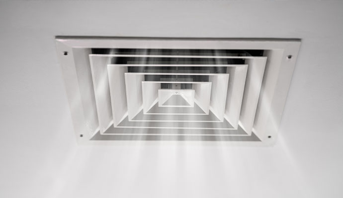 Square white HVAC ceiling diffuser with air flowing through the concentric vents