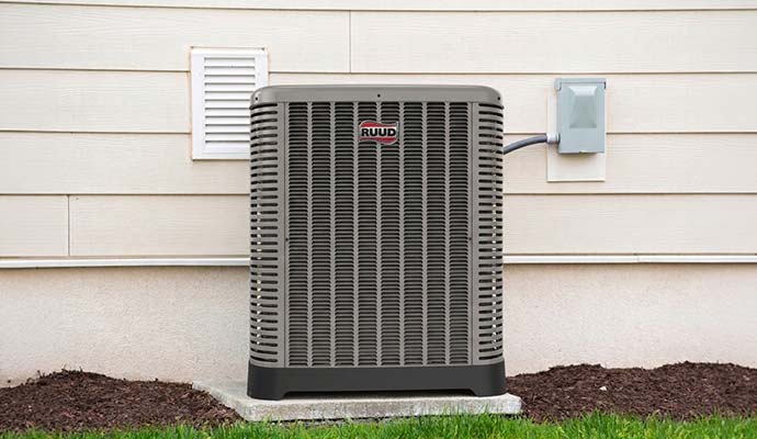Installed Ruud outdoor air conditioner beside a house.