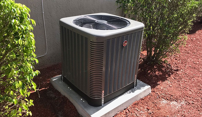 Modern outdoor air conditioning condenser unit installed on a concrete pad next to a house