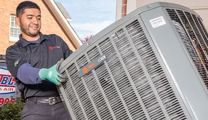 Technician installing a Trane outdoor HVAC unit.