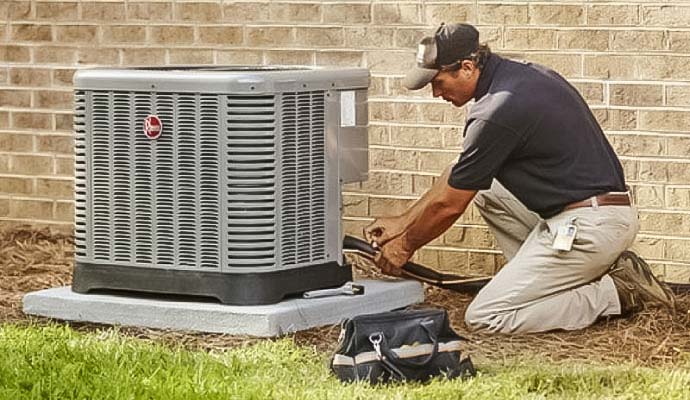 Technician servicing an outdoor Rheem air conditioner.