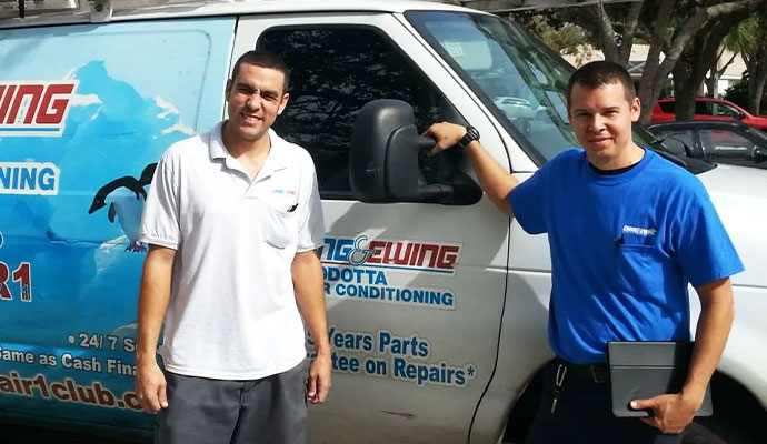 Ewing and Ewing Air Conditioning technicians standing in front of their company service vehicle