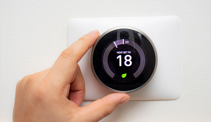 Person using thermostat temperature controls to adjust the temperature of a room