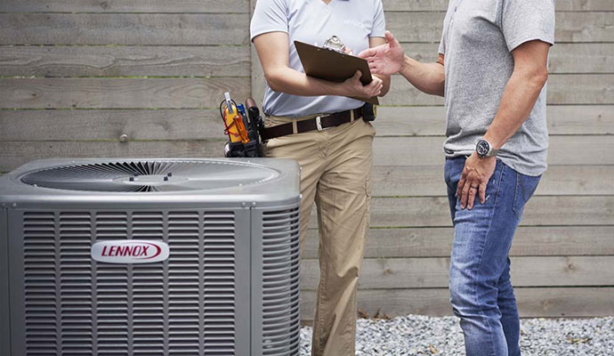 Two HVAC technician holding a clipboard next to an outdoor Lennox unit