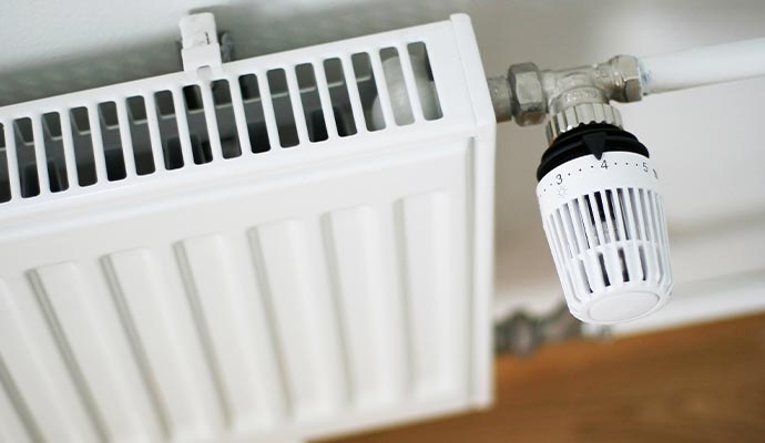 A close-up of a white panel radiator with a thermostatic A close-up of a white panel radiator with a thermostatic